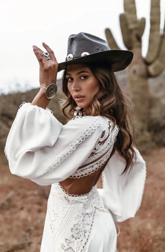 a boho bridal look with a boho fitting plain and lace wedding dress wiht a cutout back, a black leather hat with decor and some more accessories