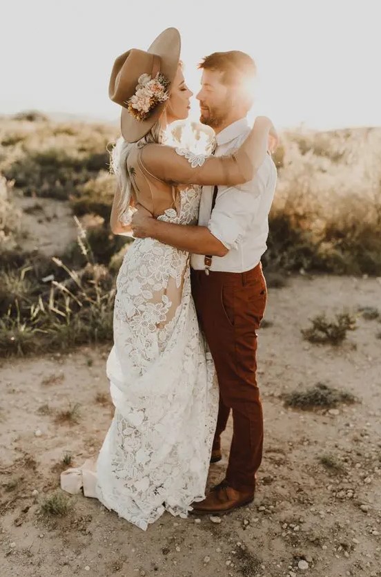 a boho bridal look with a lace applique wedding dress, a tan hat with neutral blooms and greenery is a lovely idea for a boho wedding