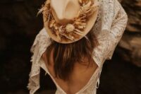 a boho bridal look with boho lace A-line wedding dress with a cutout back and bell sleeves, a tan hat with dried blooms and grass