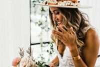 a boho bridal outfit with a boho lace fitting wedding dress with a deep neckline, a creamy hat with dried leaves and a statement bracelet