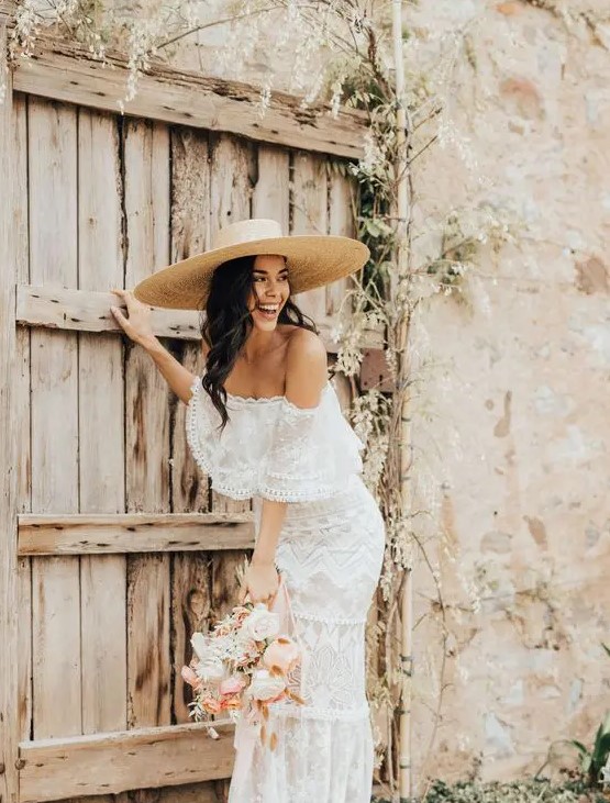 a boho destination bridal look with a boho lace off the shoulder fitting wedding dress and a wide brim hat is amazing