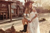 a boho rustic bridal outfit with a strapless boho lace wedding dress, a brown hat and black cowgirl boots, chic boho accessories