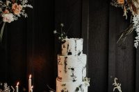 a bold modern black and white wedding cake with brushstrokes topped with dried herbs and blooms