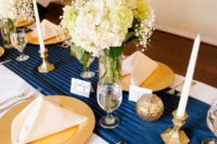 a bold navy, gold and creamy tablescape with gold chargers, balls and neutral blooms
