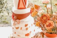 a bold wedding cake with a striped tier, brushstrokes and dimensional triangles plus fresh blooms for a boho wedding