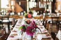a bright barn wedding table with a white runner, a bright floral centerpiece, fuchsia napkins, white porcelain