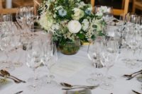 a chic barn wedding table with neutral linens, a white and blue flower centerpiece and neutral stationery