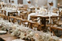 a chic barn wedidng table with a long dried foliage and blooms table runner, neutral linens and porcelain