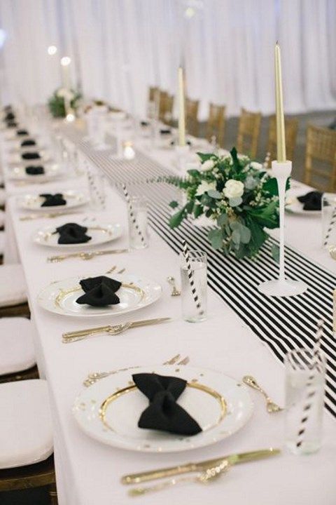 A chic black and white table settign with godl touches   candles, cutlery and touches on plates
