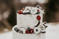 a chic white frosted wedding cake with gold leaf, white drip, berries and glazed donuts is amazing