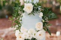 a classic textural powder blue wedding cake decorated with neutral blooms, greenery and leaves