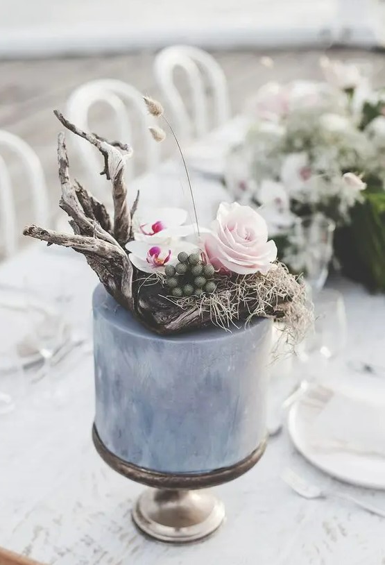 a coastal grey wedding cake with driftwood, hay, bright blooms, graases and berries is a very nonchalant and chic idea