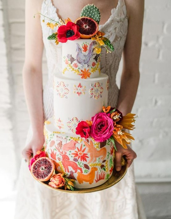 a colorful Mexican wedding cake with hand painted animals and blooms and bright blooms, citrus and cacti