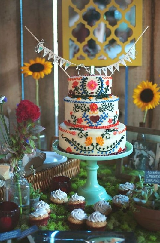a colorful Mexican wedding cake with various bright floral patterns plus a banner topper is a fun idea to try