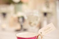 a colorful vintage teacup with an escort card is a lovely wedding favor idea that is budget-friendly