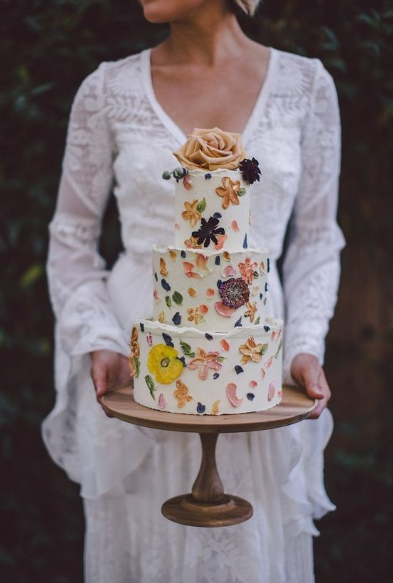 a cute and bold floral wedding cake with sugar and real petals and dried blooms plus fresh ones on top for a flower child wedding