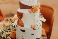 a fantastic boho wedding cake with white tiers, colorful brushstrokes, rust sugar detailing and some orange and dried blooms