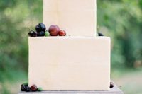 a laconic neutral square wedding cake topped with fresh fruits and berries for a modern wedding