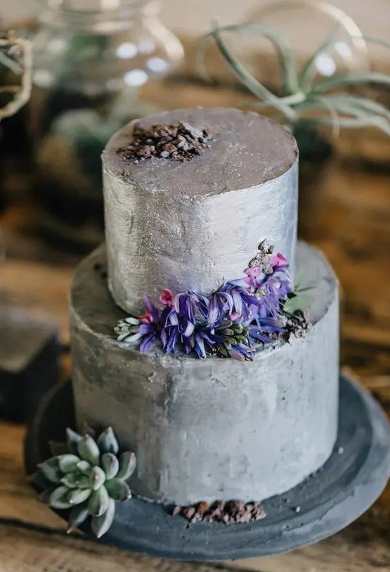 a modern secret garden wedding cake with silver grey buttercream, pirple and pink blooms and a succulent is a statement idea