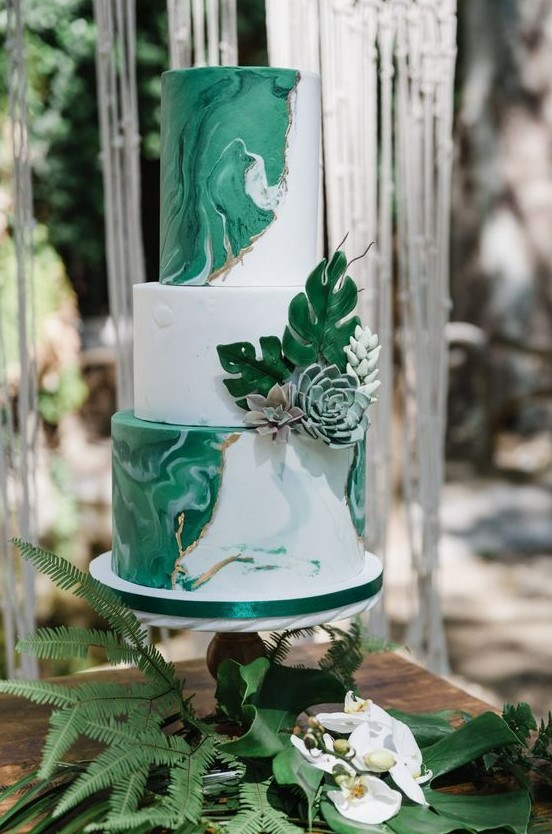 a modern tropical wedding cake with white marble and green marble tiers and sugar leaves and succulents is a very chic and cool idea