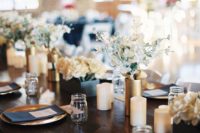 a navy and gold wedding table setting with white and gold candles, neutral blooms and gold chargers