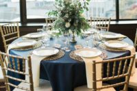 a navy, gold and creamy wedding tablescape with a lush greenery and neutral bloom centerpiece