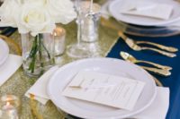 a navy, gold glitter and creamy tablescape plus gold cutlery and candle holders