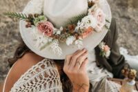 a neutral bridal hat decorated with neutral and pastel blooms, greenery and berries for a boho or woodland bride