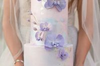 a pastel watercolor wedding cake with gold foil and purple orchids covering it is a gorgeous and cool idea to rock