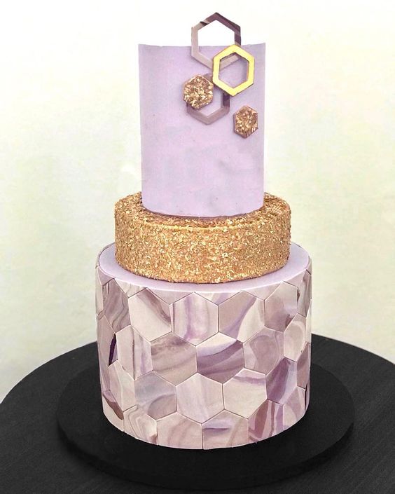 a purple and gold wedding cake with a glitter tier, a purple marble hexagon tier and a sleek one decorated with gold hexagons
