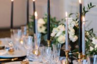 a refined black and white wedding table setting with black and white candles, neutral blooms and gold touches