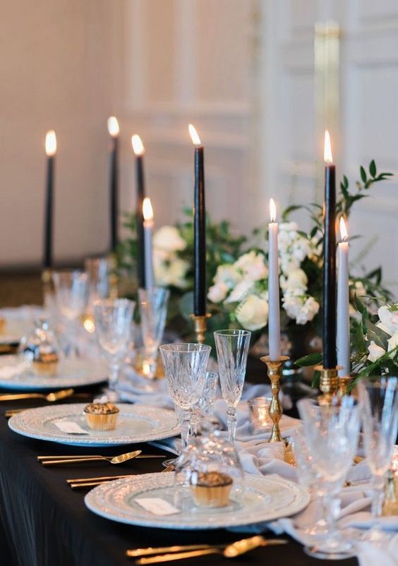 a refined black and white wedding table setting with black and white candles, neutral blooms and gold touches