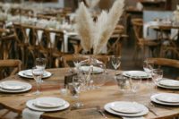 a simple and elegant barn wedding table with neutral linens, a pampas grass centerpiece and candles