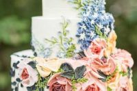 a sophisticated white wedding cake with pink and blue sugar blooms and greenery is a beautiful and chic idea for a spring or summer wedding