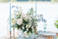 a spring wedding tablescape with a runner, napkins, powder blue and white blooms plus powder blue candles