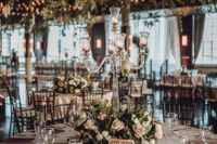 a stylish and chic barn wedding tablescape with neutral linens, a lush blush flower and greenery wedding centerpiece and a crystal candle holder
