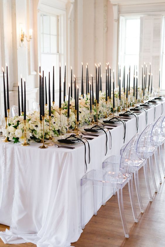 a super elegant black and white tablescape with white blooms, thin black candles and black porcelain plus napkins