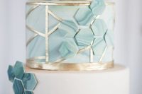a white and aqua wedding cake with gold decor, with geometric lines, aqua marble hexagons coverign all the tiers looks amazing