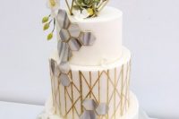 a white and gold wedding cake with grey marble hexagons, gold patterns, a himmeli topper, some white blooms and succulents