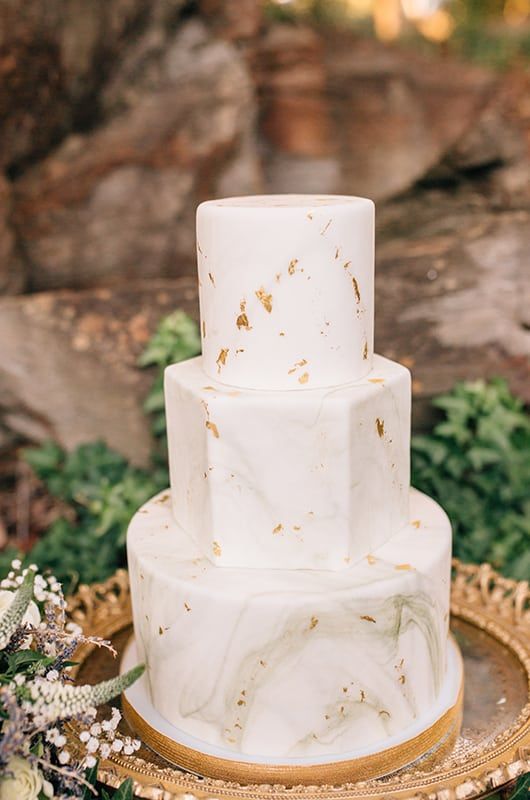 a white and grey marble wedding cake with round and a hexagon tier, with gold leaf is a lovely and cool idea for a modern wedding