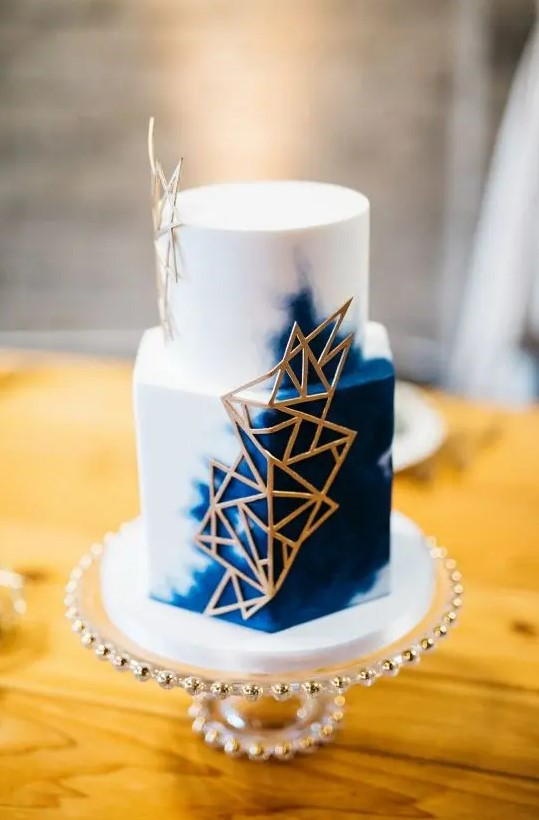 a white and navy wedding cake decorated with gold geometric touches is an amazing idea for a bold modern wedding