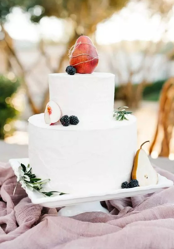 a white buttercream wedding cake with fresh apples, a pear and blackberries is a stylish idea for a fall vineyard wedding
