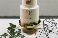 a white round wedding cake with pastel-colored triangles, some fresh greenery and a geometric gold heart is a lovely idea