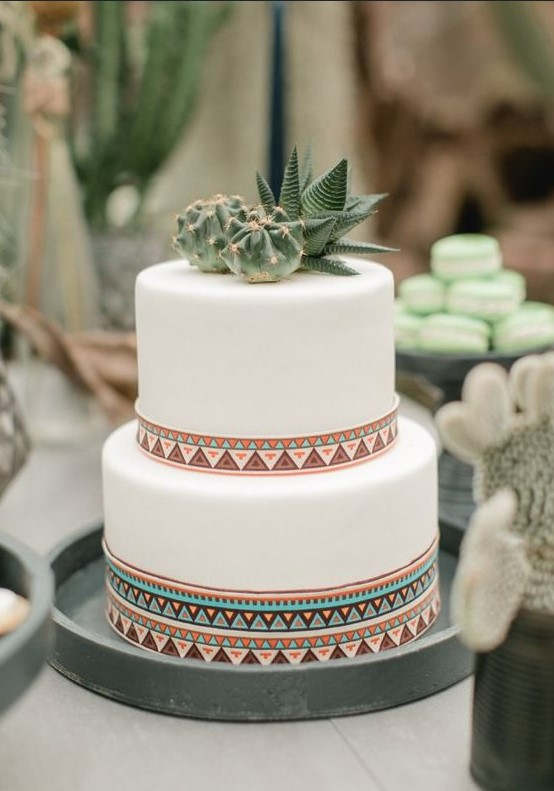 a white wedding cake with bright patterns, cacti and succulents for a boho desert wedding
