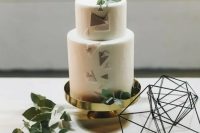 a white wedding cake with colored triangles and topped with a geometric heart and greenery