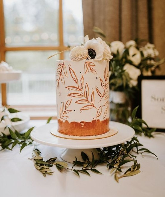 a white wedding cake with painted rust leaves and white fresh blooms on top is a beautiful idea for a modern wedding