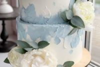 a white wedding cake with powder blue brushstrokes and neutral blooms and leaves