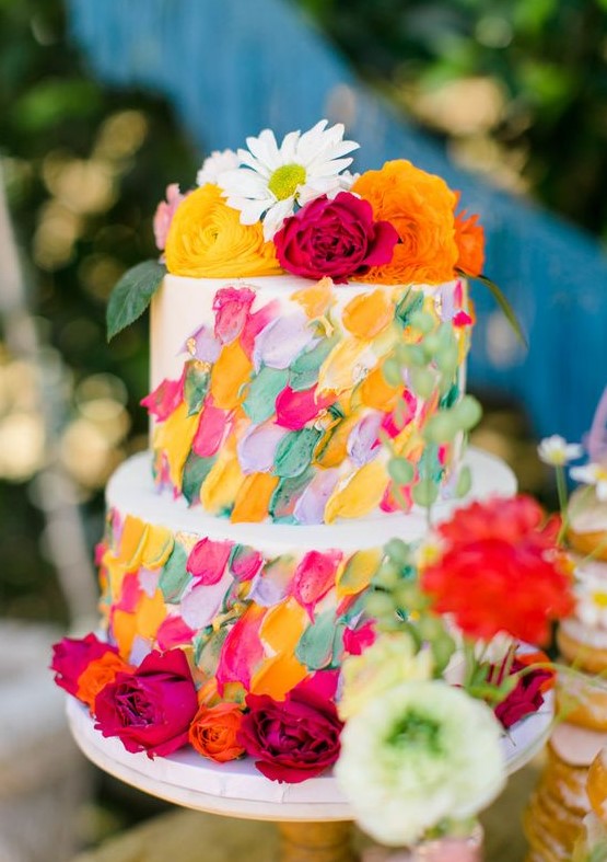 a white wedding cake with super bright textural and dimensional brushstrokes and bold blooms on top and around the cake