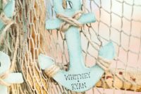 aqua-colored plywood anchors with names and rope on fishing net are very creative and bright pieces to rock
