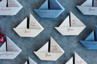 blue, grey and white paper boats as escort cards and wedding favors at the same time are a cool idea